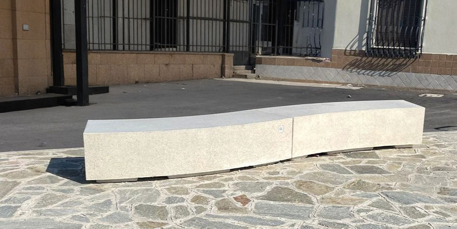 panchina in cemento armato, di forma ondulata, con rifinitura di colore sabbiato bianco.