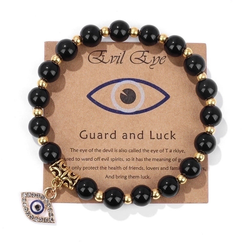 Thumbnail: A black bead bracelet with gold accents and an evil eye charm, displayed on a card labeled "Evil Eye - Guard and Luck."