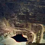 Vast open-pit Lavender Pit copper mine with dramatic multicolored terraced walls and a dark pool of water at the bottom in Bisbee Arizona.