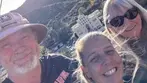 Three smiling people taking selfie at Quality Hill overlook with Bisbee town and mountains in background.
