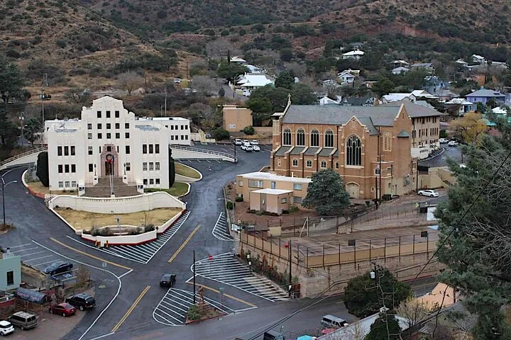 View from Quality Hill of white courthouse and brick church buildings with roads and surrounding Bisbee hills.