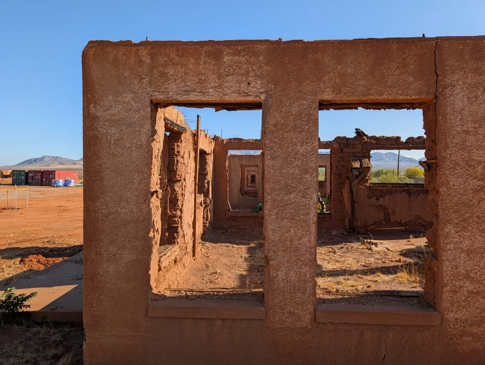 Adobe ruins of Fort Naco with rectangular window openings and desert landscape under clear blue sky.