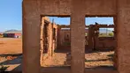 Adobe ruins of Fort Naco with rectangular window openings and desert landscape under clear blue sky.