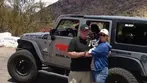 Couple holding small dog and smiling in front of gray Big Jeep Tours vehicle at Juniper Flats.