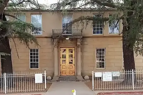 Lowell School building with ornate golden copper double doors and large trees framing entrance.