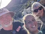 Three smiling people taking selfie at Quality Hill overlook with Bisbee town and mountains in background.