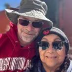 Smiling man in bucket hat and woman in beanie taking selfie together on sunny day in Bisbee.