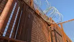 Close-up view of the steel US-Mexico border wall fence and razor wire near Bisbee, visited on a Big Jeep Tours educational excursion.