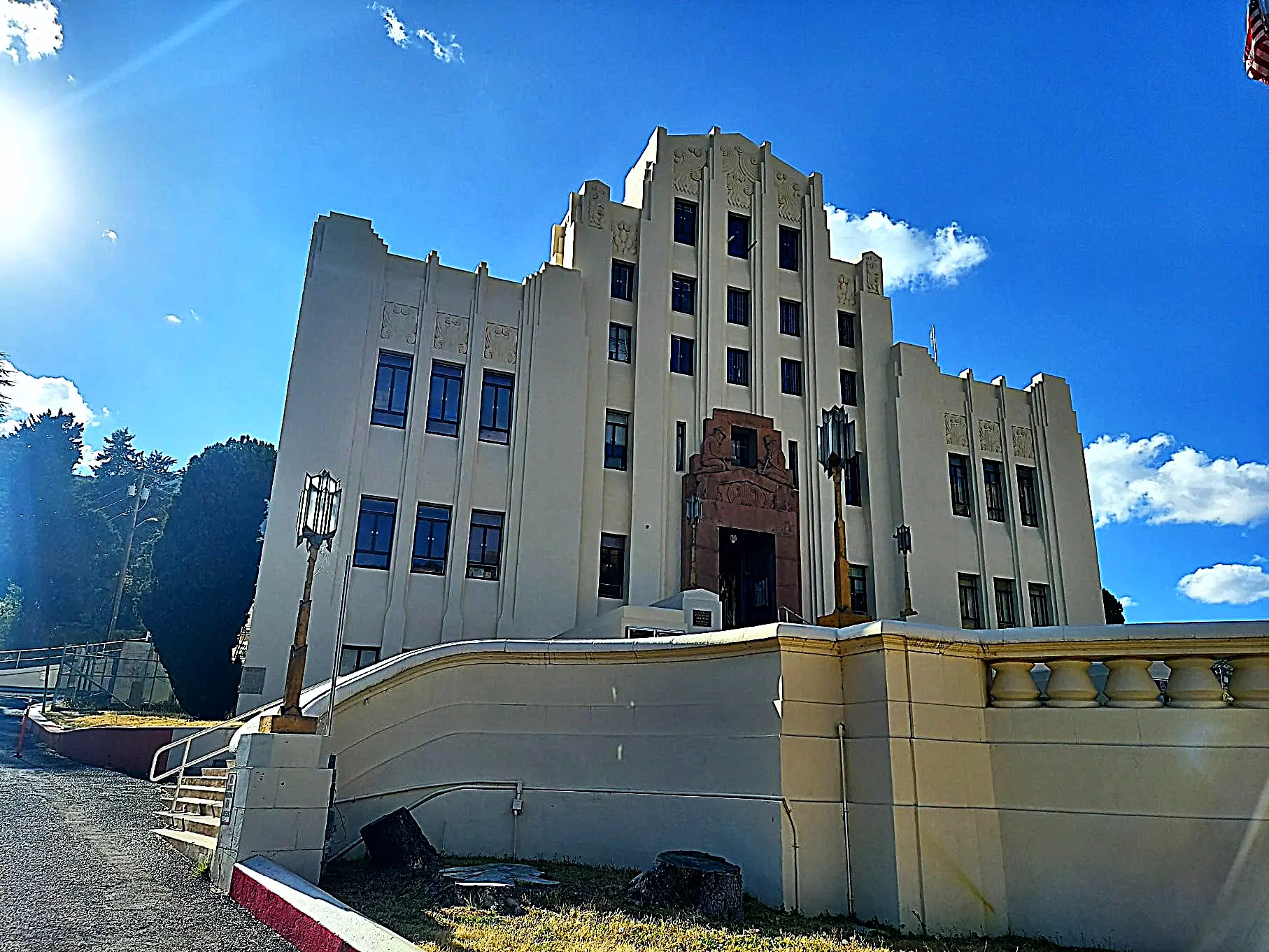 Large, white art deco building with square windows and a clear blue sky.
