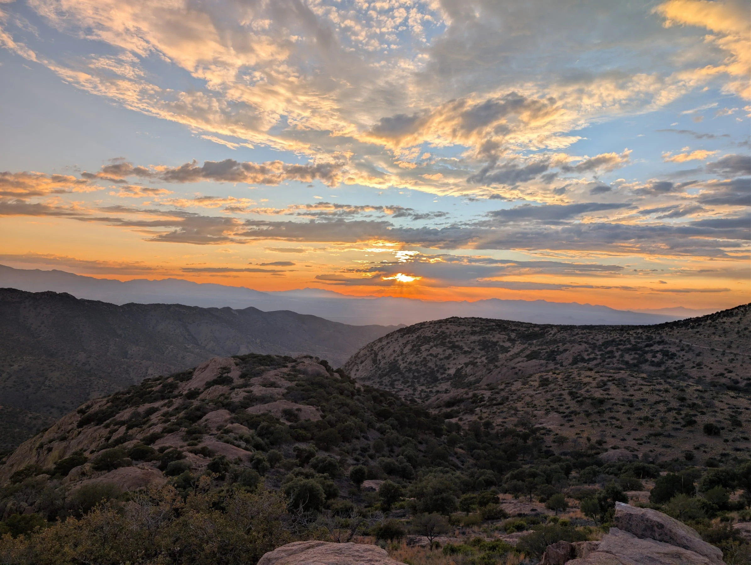 Dramatic sunset with vibrant orange and pink clouds over layered mountain ridges from Juniper Flats in Bisbee.
