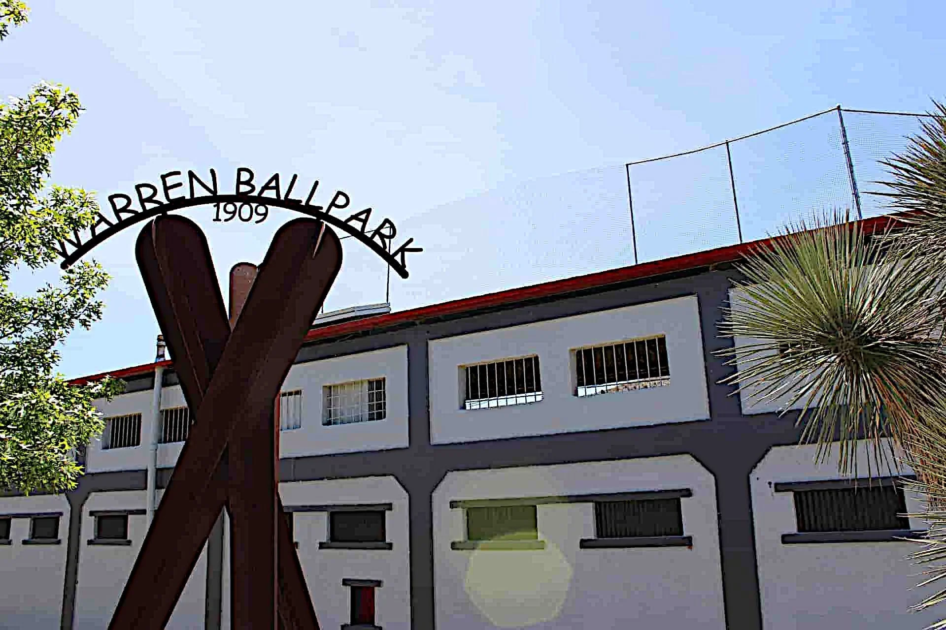 Warren Ballpark 1909 sign with historic stadium building and palm tree against blue sky in Bisbee.