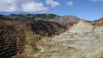 Vast open-pit copper mine with colorful terraced walls of red, brown, and white rock rising against desert mountains near Bisbee.