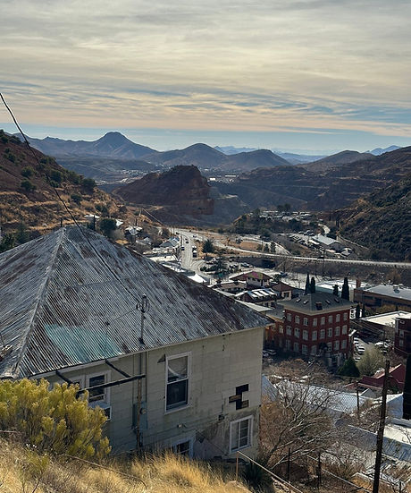 Panoramic valley overlook of Bisbee town nestled among colorful hills and mining ruins, with distant mountains beyond. Big Jeep Tours.