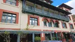 Historic Copper Queen Hotel building with green balconies, red brick trim, and blue SUV parked in front under blue sky.