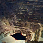 Vast open-pit Lavender Pit copper mine with dramatic multicolored terraced walls and a dark pool of water at the bottom in Bisbee Arizona.