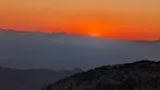 Close-up of a vibrant red and fiery orange sky as the sun dips behind distant mountain peaks near Bisbee.