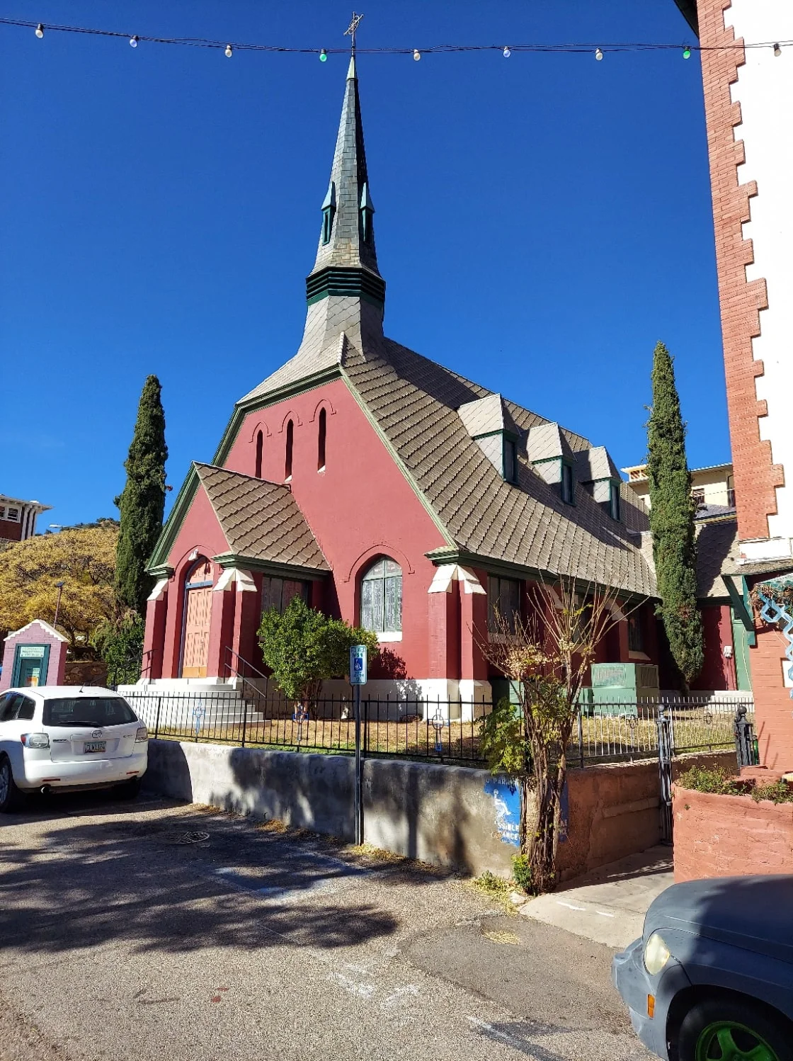 Maroon brick church with tall slender gray dome and a clear blue sky.