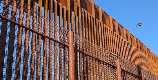Brown, rusty, steel border wall in Naco with blue sky background.
