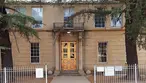 Front view of the historic Lowell School building featuring prominent golden copper double doors at the entrance, framed by large trees.