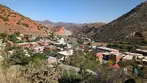 Wide panoramic high road view of Old Bisbee town nestled in colorful hills under blue sky.