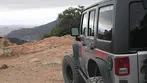 Gray Big Jeep Tours vehicle parked on rocky Juniper Flats overlook with mountain range in background.