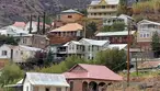 Colorful historic houses and buildings on steep Opera Hill slope in Bisbee with desert mountains in background.