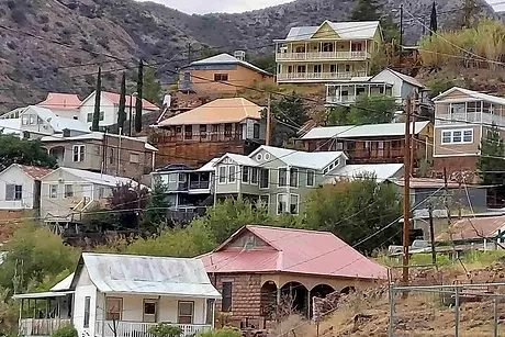 A cluster of historic colorful houses built vertically onto a steep desert hillside in Bisbee, Arizona.