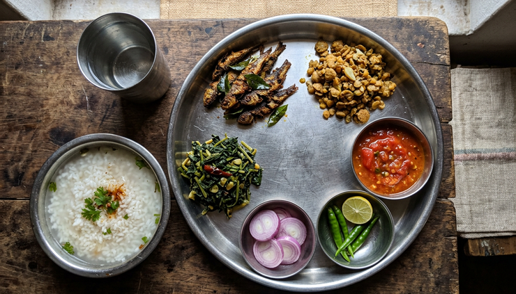 Overhead view of a Sambalpur meal with pakhala, fried fish, saag, and chutney