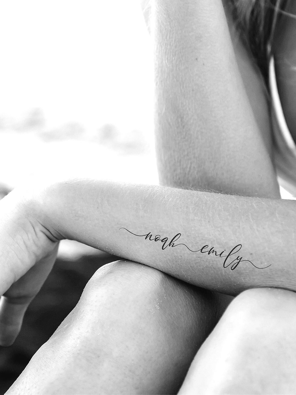 Fineline Tattoo Vorlage mit geschwungenen Kindernamen auf weiblichem Unterarm