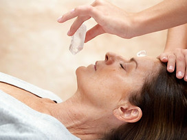 Crystal healing and Reiki‑based Pranic Renewal Ritual with a practitioner using clear quartz over the client’s third eye. 