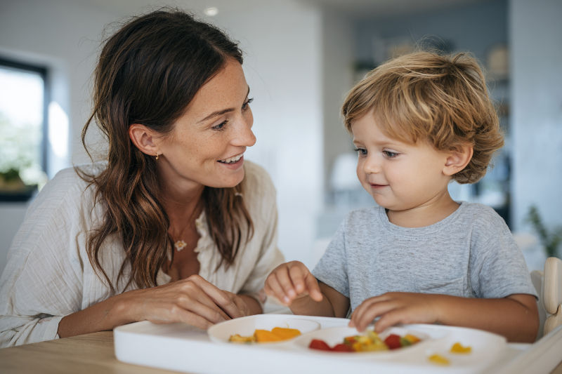 Mother encouraging toddler during mealtime