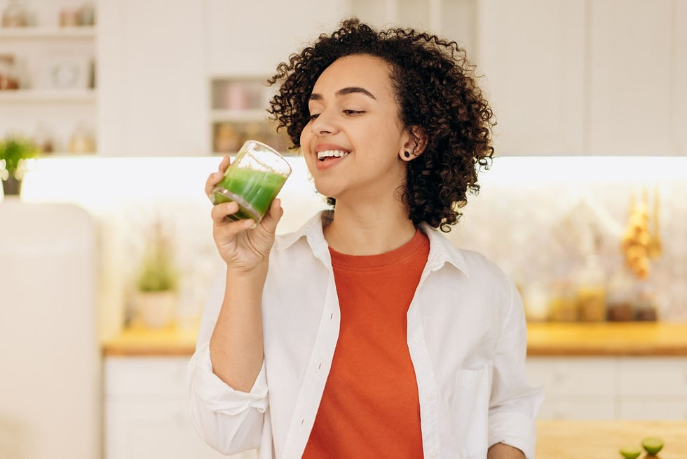 Smiling woman with curly hair holding a green smoothie