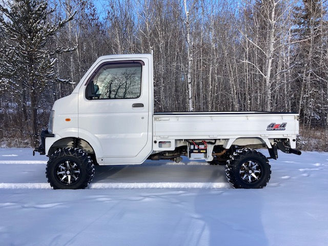 Modified White Suzuki Carry Mini Truck from the left side. 