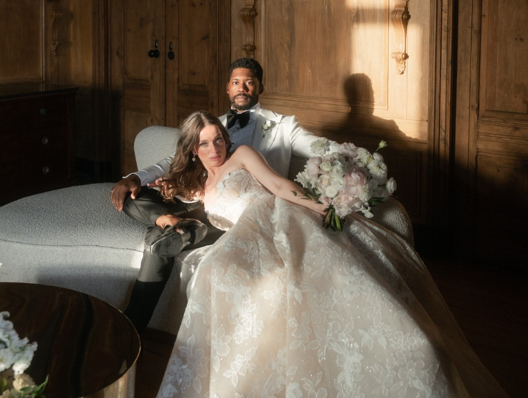 Groom seated on the sofa with the bride lying down with her head in his lap in an editorial photo.