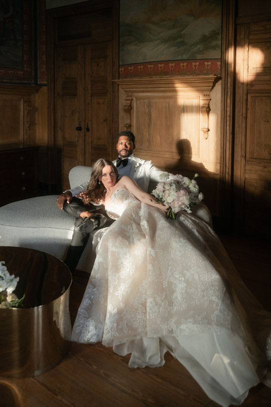 Groom seated on the sofa with the bride lying down with her head in his lap in an editorial photo.