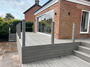 Light Grey Composite decks with glass door and brick building background Dk Landscapes Nottin.