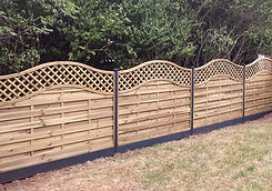 Bow Top Wooden fence with decorative trellis Tops with Grey Metal Fence posts in a grassy backyard setting.