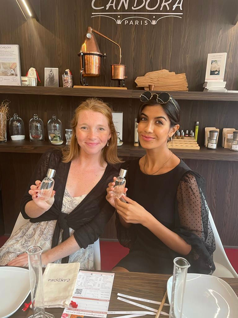 Amby e la sua amica sorridono mentre tengono in mano i profumi realizzati da Candora a Parigi