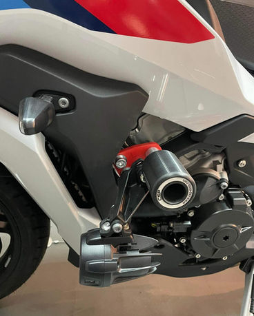 Szczegół motocykla BMW: biała, czerwona i niebieska grafika, czarny element ochronny.