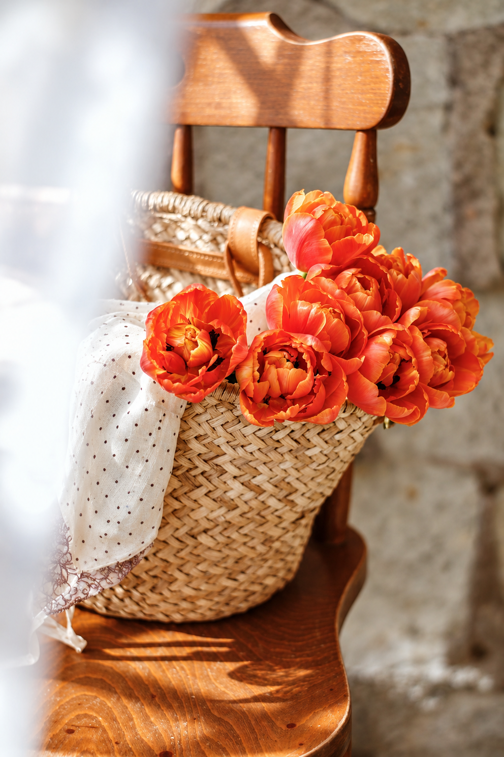 Fleurs orange dans un panier tressé posé sur une chaise en bois.