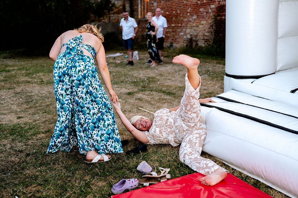 Guests bouncing on bouncy castle at Norfolk summer wedding