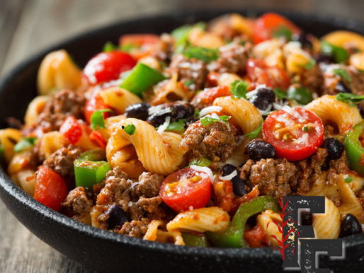 Bowl of Tex-Mex pasta salad with ground beef, black beans, cherry tomatoes, and green peppers mixed into spiral pasta.