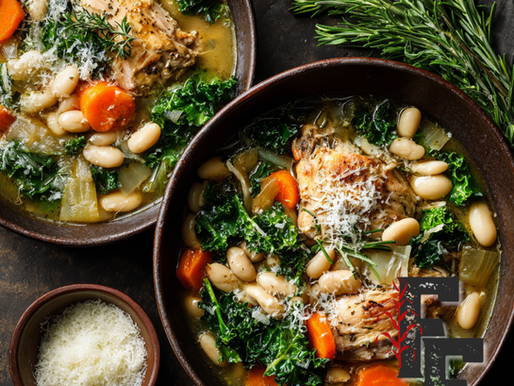 Bowl of chicken and white bean stew with kale and Parmesan, drizzled with olive oil and topped with parsley.