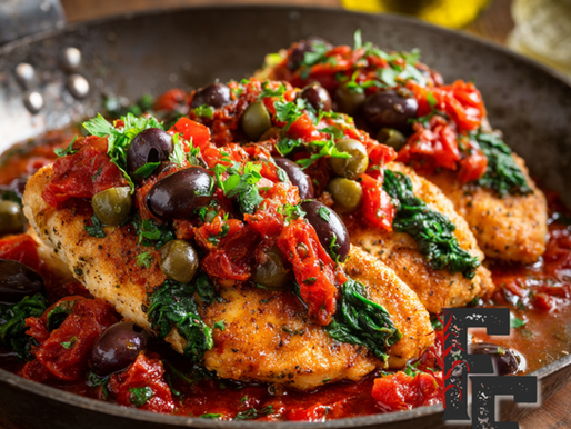 Chicken cutlets topped with tomatoes, spinach, olives, and capers in a skillet.
