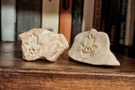 Hamsa symbol engraved on small Jerusalem stone pieces for a shelf decor.