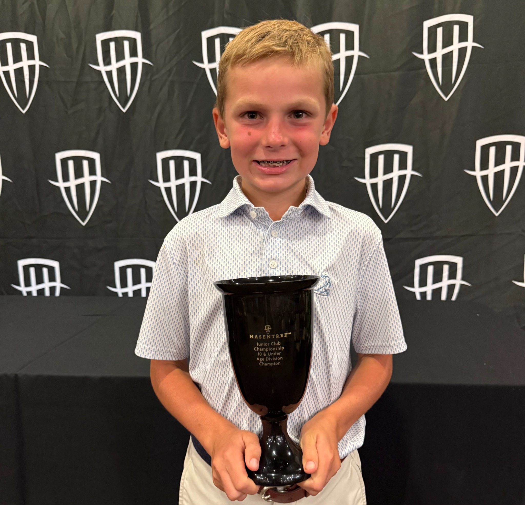 Junior golfer holding championship trophy
