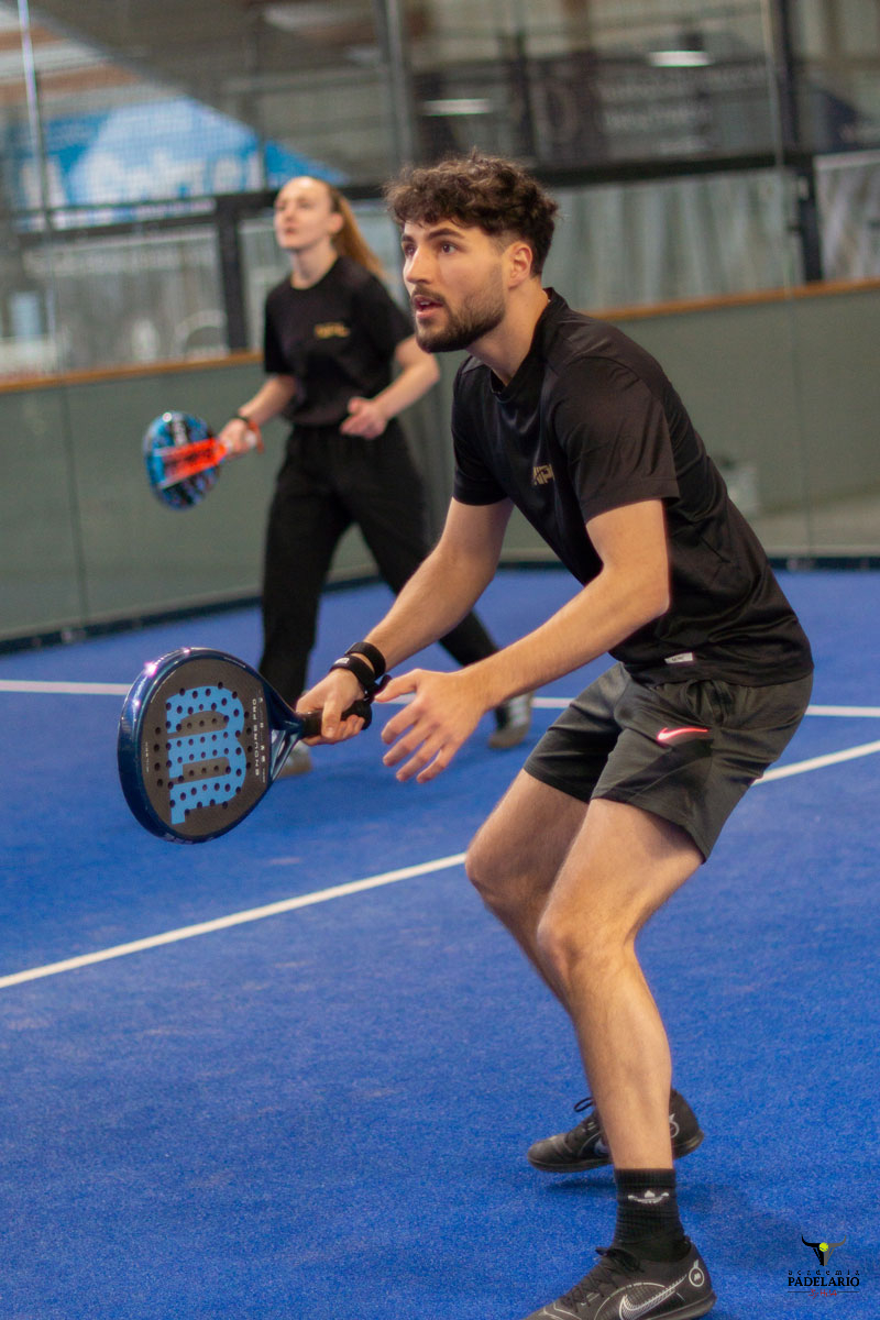 Mann und Frau spielen Padel auf blauem Platz mit Schlägern.