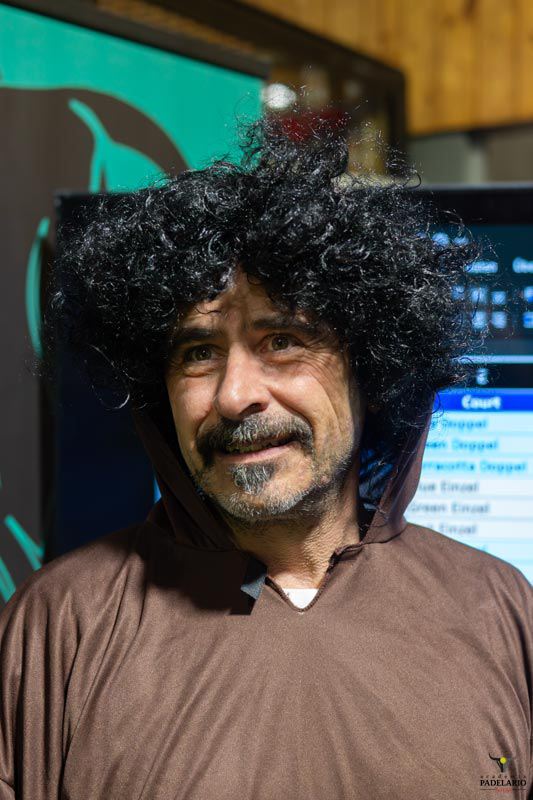 Mann mit lockigem Haar und Bart, braunem Umhang in einer Veranstaltung.