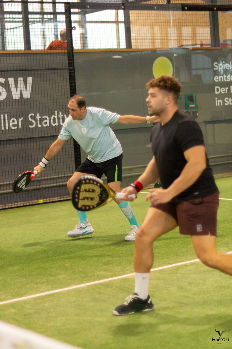 Zwei Männer spielen Padel. Banner KSW voller Stadt im Hintergrund.