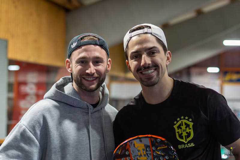 Zwei lächelnde Männer posieren zusammen, tragen Hüte und ein Brasilien-T-Shirt.